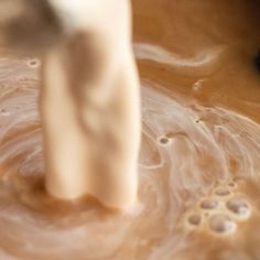 a close up of a person mixing food in a bowl with a mixer attachment on it