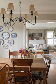 a dining room table and chairs with plates on the wall behind them in front of a couch