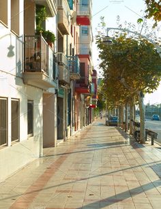 an empty city street lined with apartment buildings and balconies on either side of the road