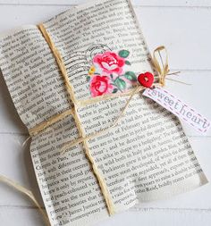 an open book with flowers on it and a tag attached to the pages that have been folded