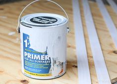 a white paint can sitting on top of a wooden table next to plywood boards