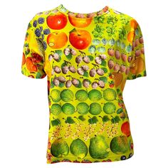 Presenting a vibrantly printed green t-shirt designed by Tom Ford for Gucci's Spring/Summer 1996 collection. The fruit print features the Gucci signature cleverly placed as stickers on the fruit. This rare and collectible shirt references Gucci's printed scarves. Approximate measurements: Size - M Bust: 42” Waist: 38” Shoulder to hem: 23.5” 100% cotton Casual Green Tops With Digital Print, Green Digital Print Top For Summer, Green Graphic Tee With Fruit Print, Green Short Sleeve Top With Fruit Print, Gucci By Tom Ford, Printed Scarves, Gucci Spring, Green T Shirt, Fruit Print