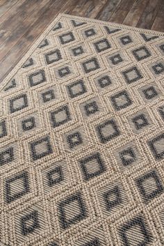 a rug on the floor with black and white squares in it, next to a wooden floor