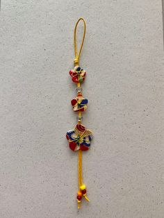 three colorful beads hanging from a string on a white surface in the shape of a flower