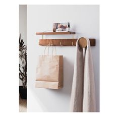 two bags hanging on the wall next to a towel rack and coat rack with hooks