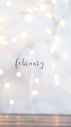 a wooden table with a blurry background and the word february written on it in cursive writing