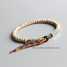 the beaded bracelet has a tasseled cord with a name tag on it