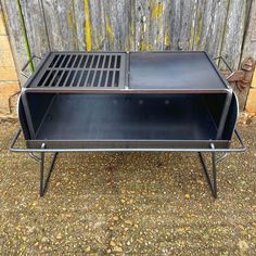 an outdoor bbq grill sitting on top of a gravel ground