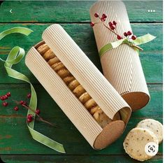 some crackers are sitting in a box on a wooden table next to a green ribbon