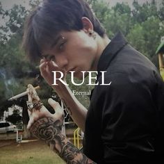 a man with tattoos on his arm holding a cell phone to his ear and the words ruel in front of him