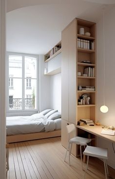 a bedroom with a bed, desk and chair next to a window in the room