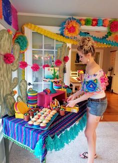 a woman standing in front of a table filled with cupcakes and desserts