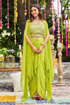 Neon green blouse featuring sweetheart neckline, sleeveless design, and intricate embroidery with cutdana, pearls, sequins, crystals, and tassels. Paired with a matching solid draped skirt and a drop shoulder cape with tassel edges., Fit: Relaxed Pearls Blouse, Sweetheart Blouse, Embroidery Pearls, Tassel Embroidery, Shoulder Cape, Georgette Blouse, Draped Skirt, Women Skirt, Green Pearls