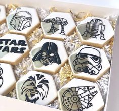 star wars decorated cookies in a box with gold foil and white frosting on them