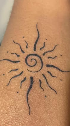 a sun tattoo on the back of a person's arm, with black ink