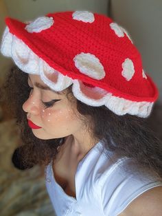 a woman wearing a red and white crocheted hat with polka dots on it