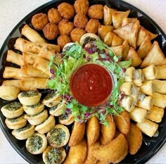 an assortment of appetizers on a platter with dipping sauce