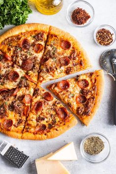 a pizza sitting on top of a table next to cheese and pepperoni toppings