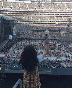 a woman holding up a white frisbee in front of an empty stadium