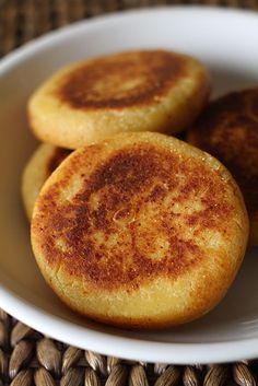 three pancakes on a white plate sitting on a wicker place mat