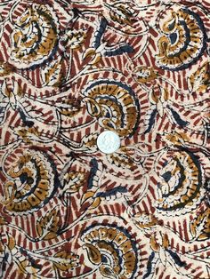 a button is on the side of a patterned cloth with an ornate design in red, yellow and black