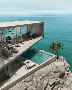 an aerial view of a house overlooking the ocean with a swimming pool and lounge chairs