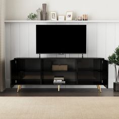 an entertainment center with a large flat screen tv on it's stand, in front of a white paneled wall