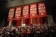 a large group of people standing on top of a basketball court with banners above them