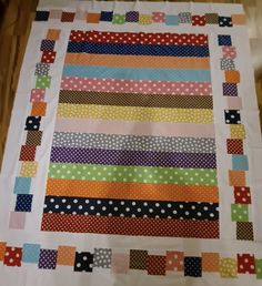 a multicolored patchwork quilt with polka dots and strips on the border,