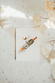 a card with an image of a champagne bottle on it next to some flowers and leaves