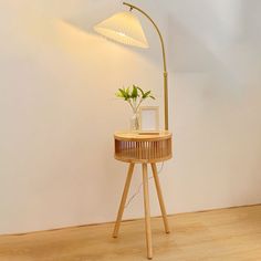 a wooden table with a plant on it and a lamp in the corner next to it