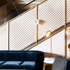 a blue couch sitting in front of a stair case next to a table and chair