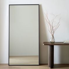 a mirror sitting on top of a wooden table next to a vase