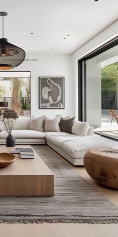 a modern living room with white couches and wooden tables in front of large windows