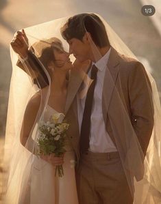 a bride and groom are standing under a veil with their heads close to each other