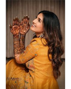 a woman is smiling and holding her hands up to show the henna designs on her hand