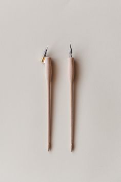 two small toothpicks sitting next to each other on top of a white surface