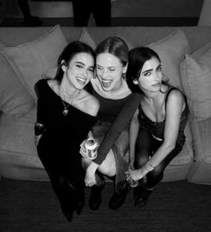 three young women sitting on top of a couch next to each other