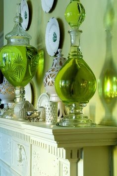 green glass vases sitting on top of a mantle