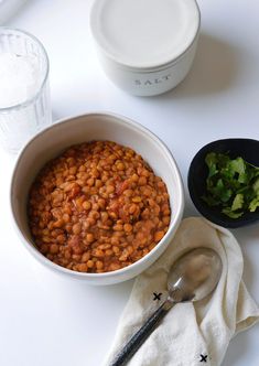 a bowl of baked beans next to a glass of water