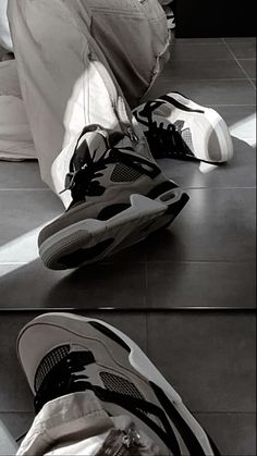 a pair of shoes sitting on top of a floor next to a person's feet