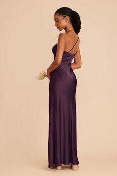 a woman in a long purple dress is looking down at the back of her gown