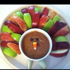 a white plate topped with candy apples and fruit shaped like a turkey next to a cup of chocolate