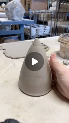 someone is making a vase out of clay on a workbench with other items in the background