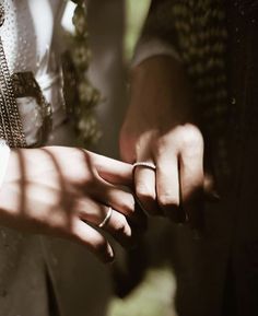 two people holding hands with rings on their fingers