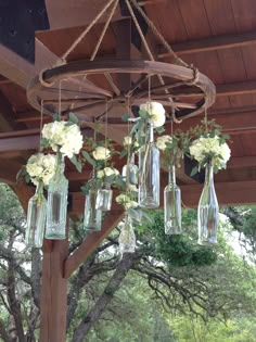 a chandelier with flowers and vases hanging from it's sides in front of a wooden structure