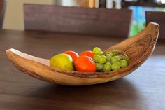 a wooden bowl filled with fruit on top of a table