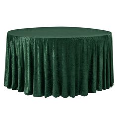 a round table covered in green velvet with pleated skirting on the top and bottom