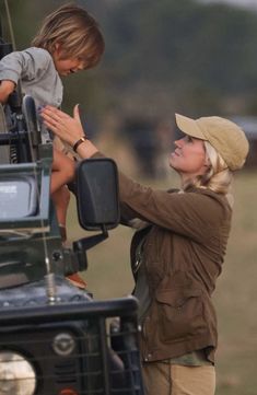 a woman and child are standing on the back of a truck with their hands together