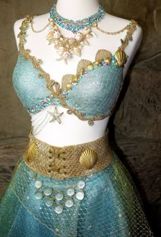 a mannequin is dressed up in blue and gold with jewelry on its chest